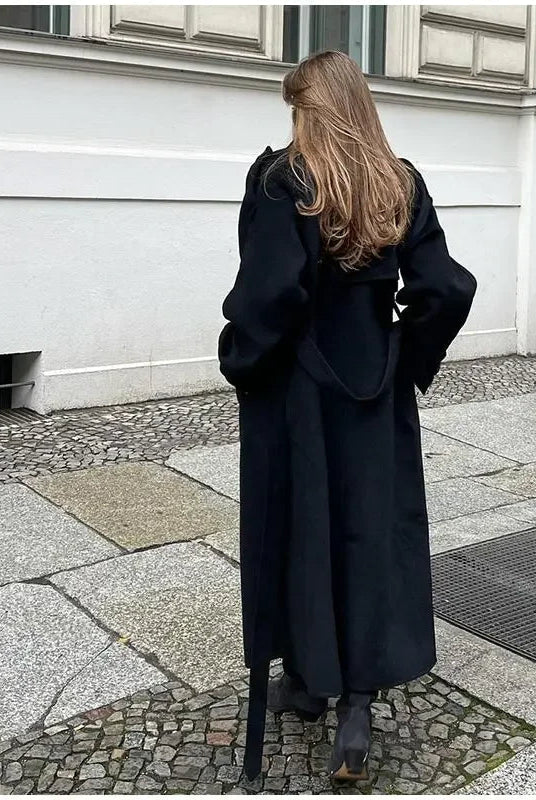 Black double-breasted trench coat with belted waist from Lumina Wear, shown on a model with classic lapels and stylish silhouette.