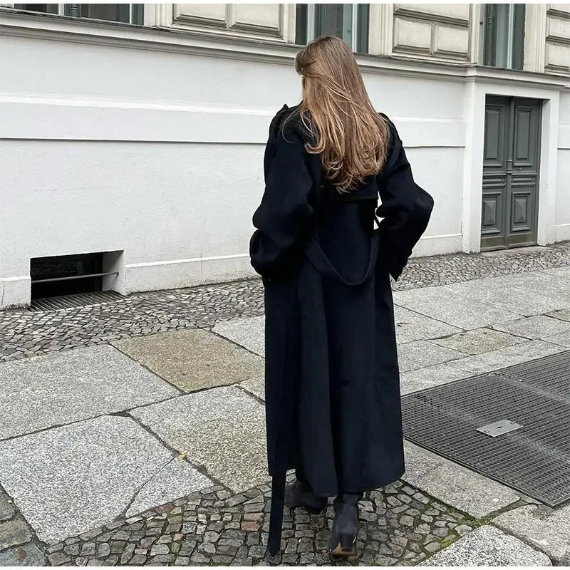 Black double-breasted trench coat with belted waist from Lumina Wear, shown on a model with classic lapels and stylish silhouette.