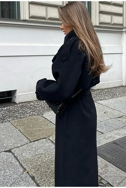 Black double-breasted trench coat with belted waist from Lumina Wear, shown on a model with classic lapels and long sleeves.