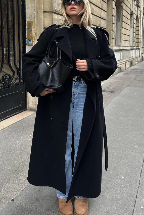 Black double-breasted trench coat with belt at waist, from Lumina Wear Cheri collection, styled with classic lapels and sleek fabric.