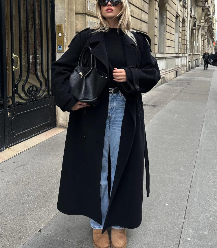 Black double-breasted trench coat with belt at waist, from Lumina Wear Cheri collection, styled with classic lapels and sleek fabric.