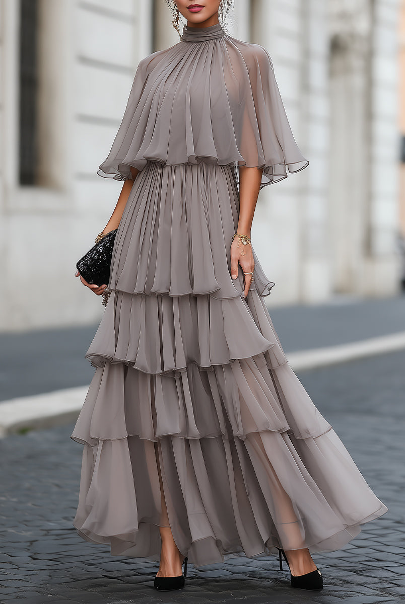 Elegant Verona maxi dress by Lumina Wear featuring tiered pleats and a sheer cape overlay, worn by a model.