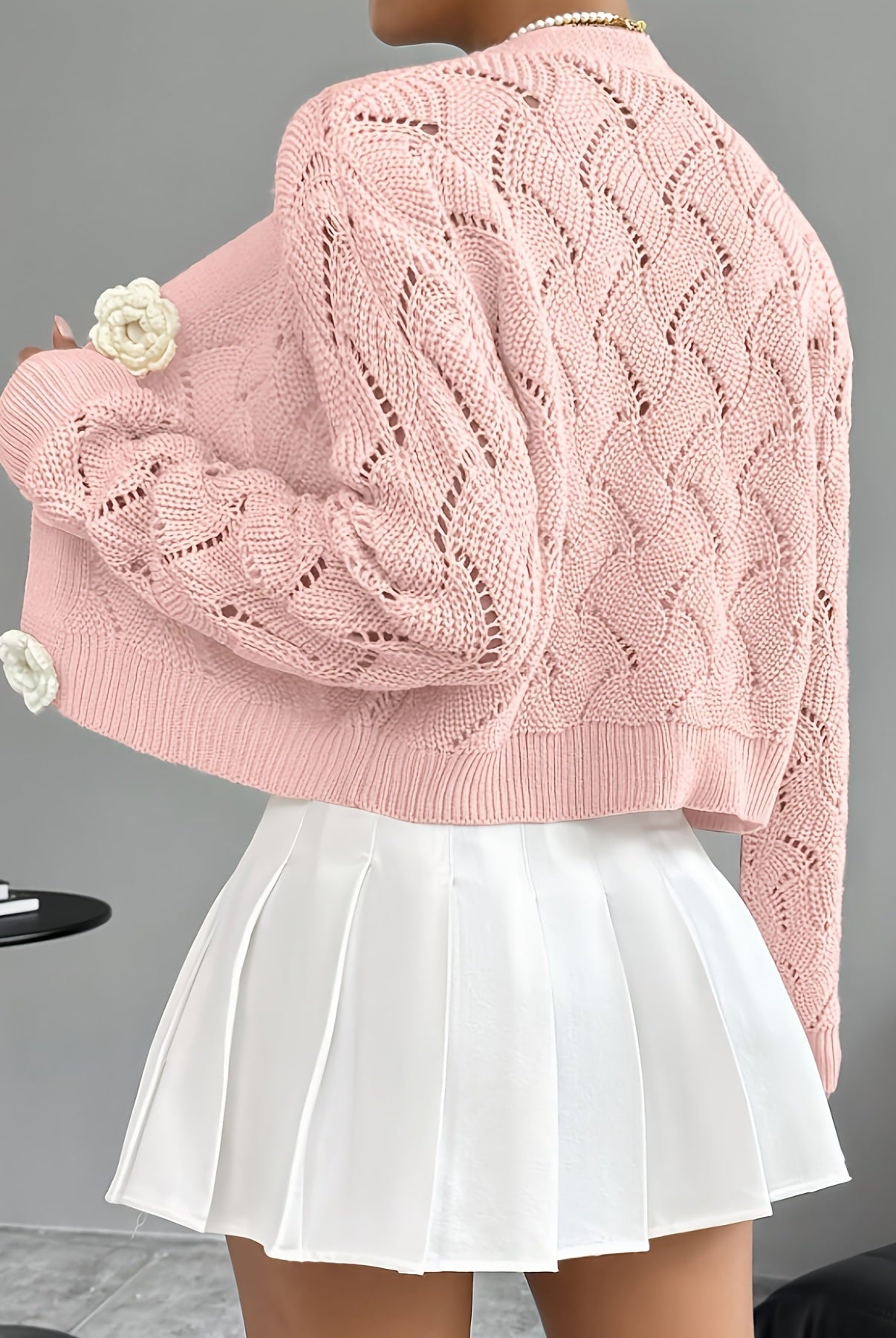 Elegant white crochet cardigan with floral buttons from Lumina Wear, featuring intricate knitting and delicate button details.