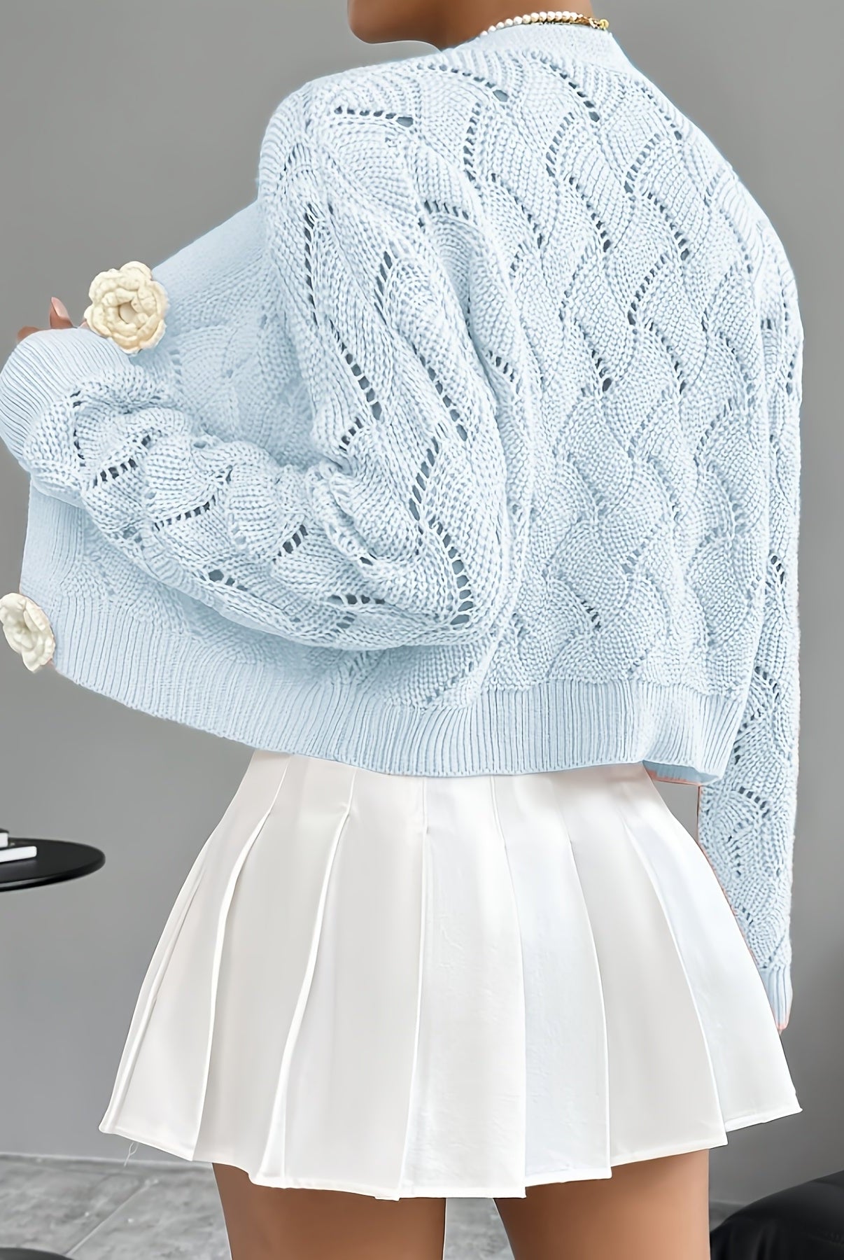 White crochet cardigan with floral buttons from Lumina Wear, featuring an elegant design and intricate knit pattern.