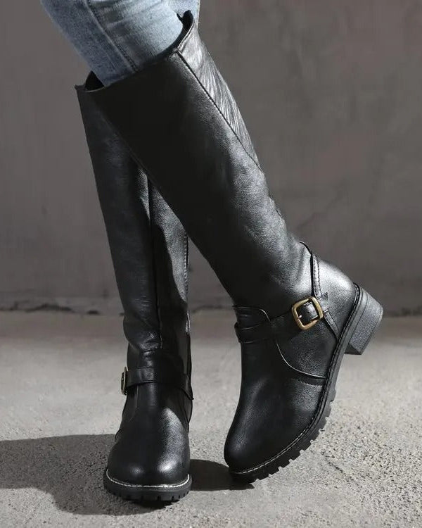 Knee-high Lumina Wear Isabella boots with buckle straps and side zipper, featuring stylish black leather design and chunky heel.