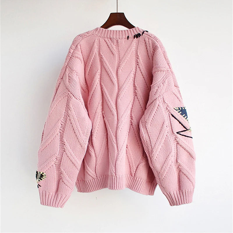 Oversized knit cardigan with bold patchwork design, colorful buttons, and Lumina Wear branding, shown in a cozy, stylish setting.
