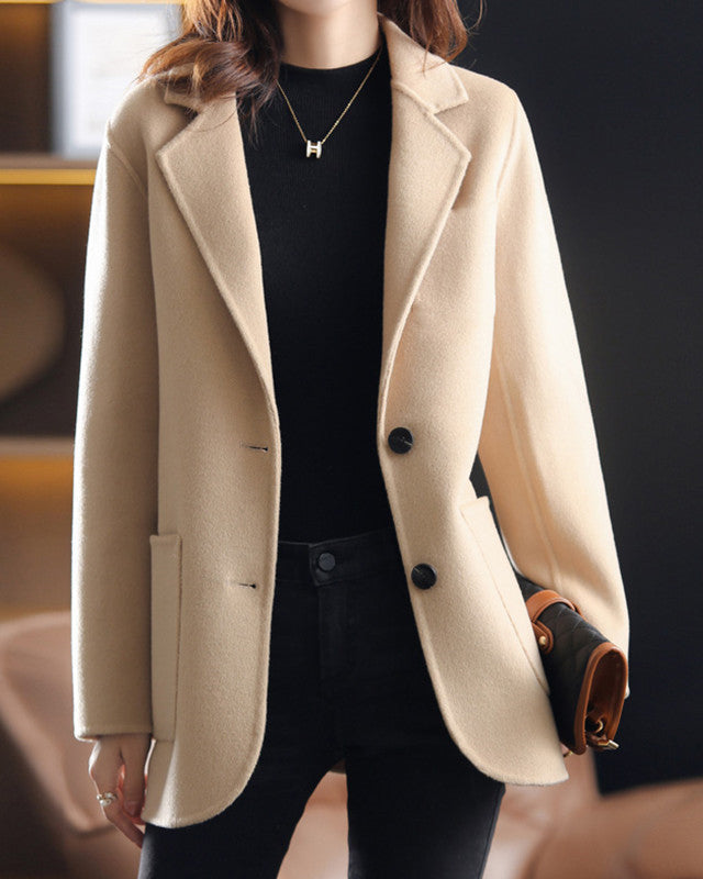 Elegant Lumina Wear Valentina wool coat with relaxed fit and lapel collar, shown hanging on a wooden coat rack.