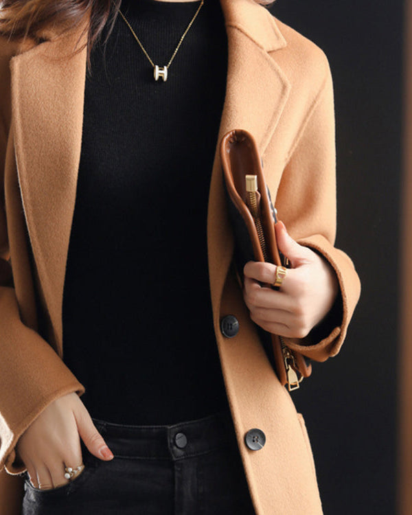 Elegant Lumina Wear Valentina wool coat with relaxed fit and lapel collar, shown hanging on a wooden coat rack.