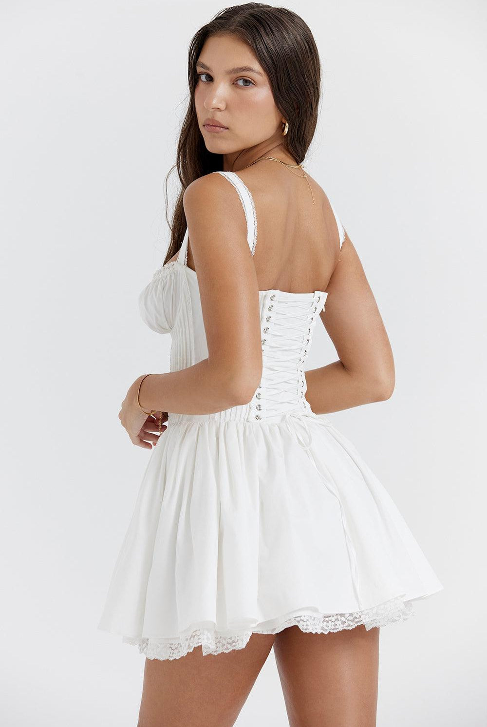 White mini dress by Lumina Wear with lace-trim bodice and short sleeves, shown on a dress form.