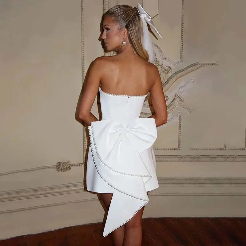 White strapless satin mini dress by Lumina Vancouver, model Anneli, shown on a hanger with a smooth, elegant fabric surface.