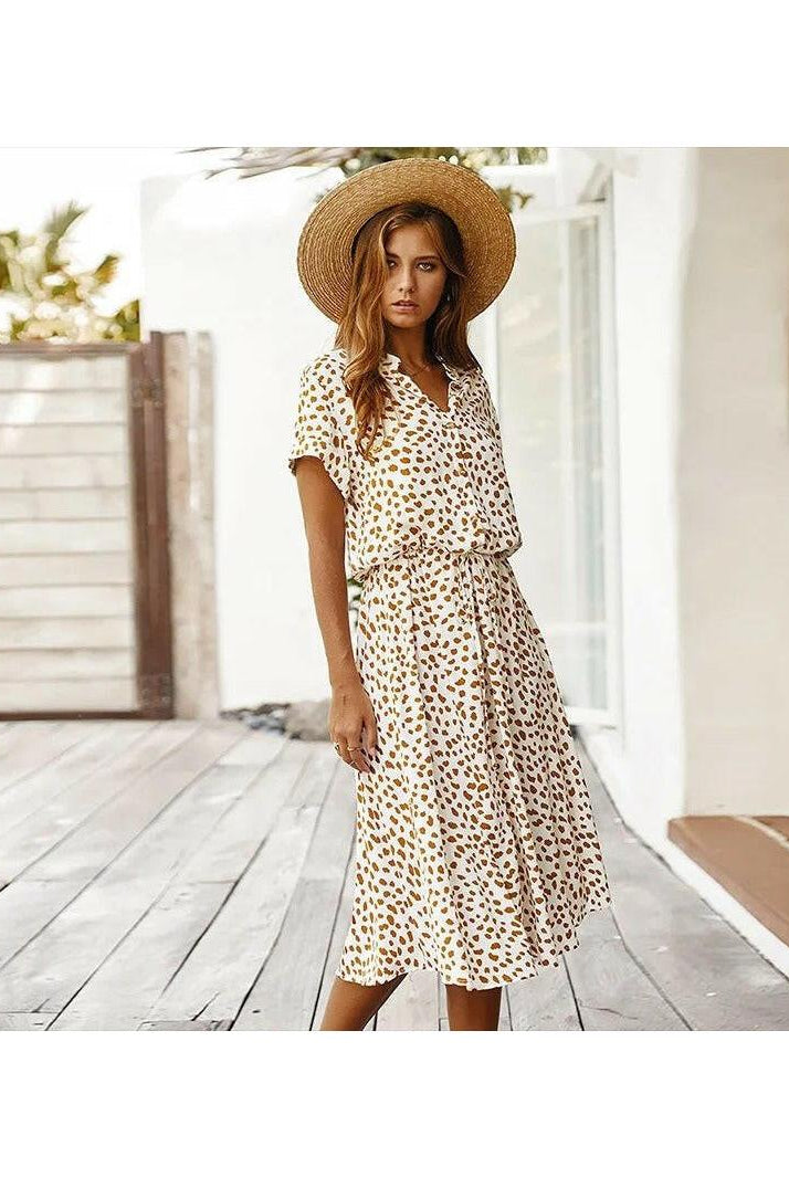 A white printed summer dress by Lumina Wear featuring a flowing design, perfect for warm weather, displayed on a hanger.