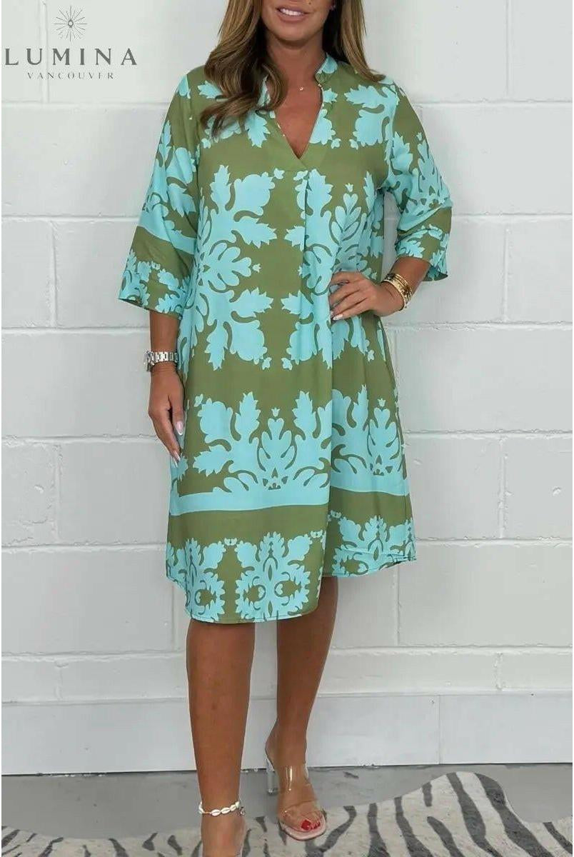 Blue and army green Bergljot spring dress by Lumina Wear featuring a flowy design and floral print, displayed on a hanger.