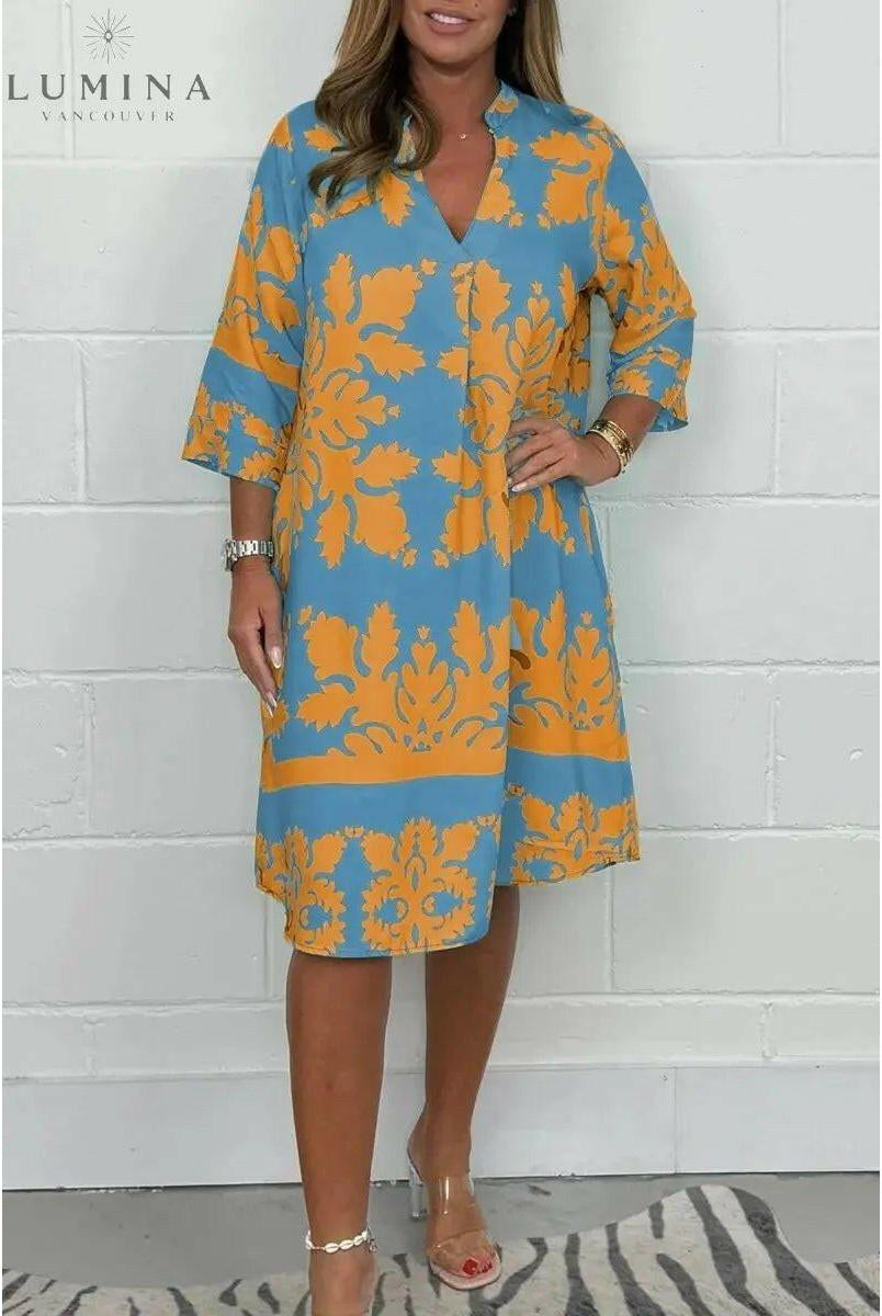 Blue and army green spring dress by Lumina Wear with a flowy design, shown on a model in a natural outdoor setting.