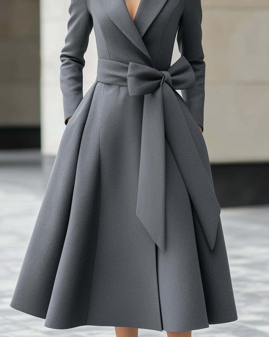 Grey Yvette A-line coat dress with bow belt detail by Lumina Wear, shown on a mannequin in a city setting.