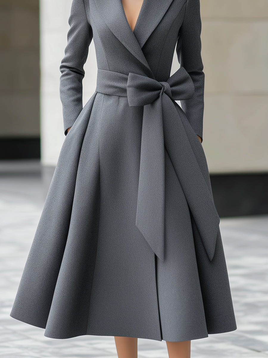 Grey Yvette A-line coat dress by Lumina Vancouver with bow belt detail, shown on a model in a stylish outdoor setting.