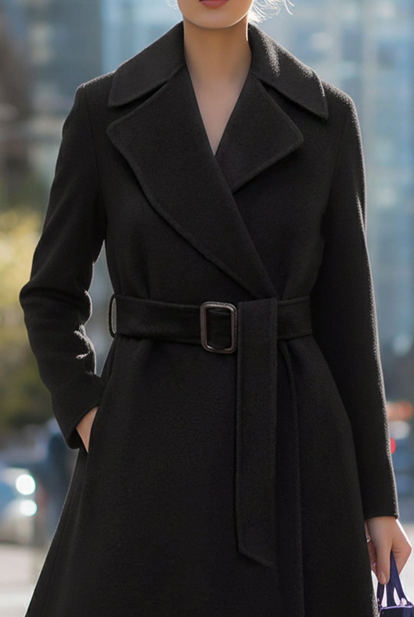 Black Lumina Vancouver Edith wool-blend midi coat with belted lapel collar, shown on a model in a stylish outdoor setting.