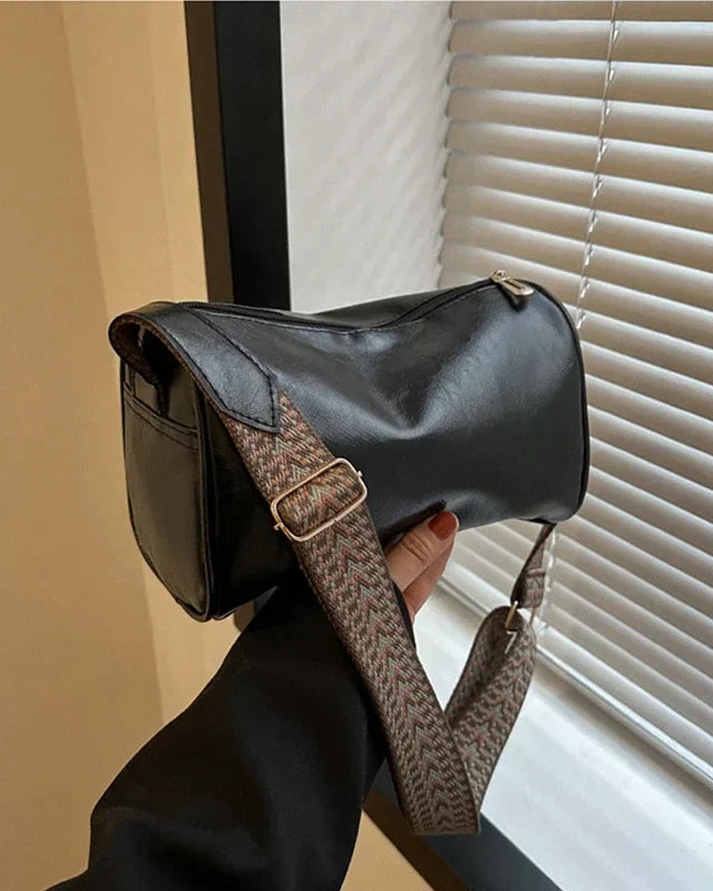 Black Lumina Florence minimalist crossbody handbag with patterned strap, featuring a sleek design and adjustable strap length.