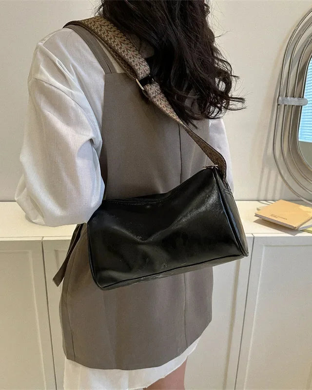 Lumina Florence minimalist black crossbody handbag with patterned strap, featuring a sleek design and adjustable strap length.