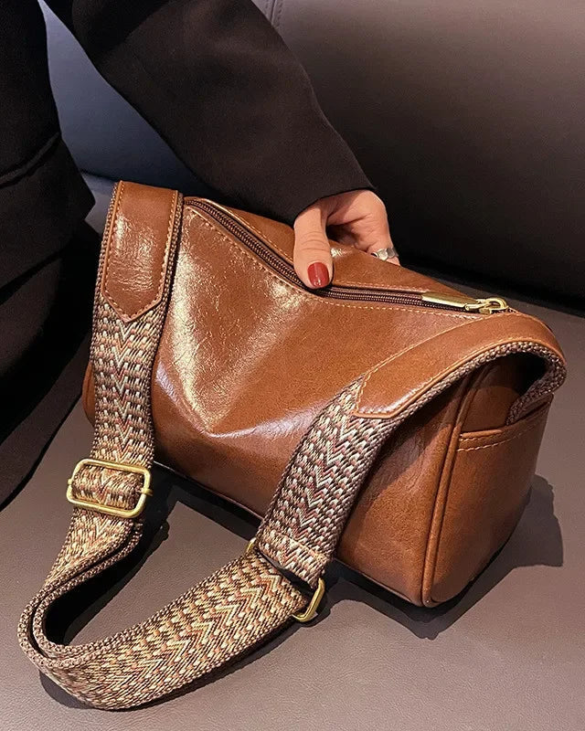 Black Lumina Florence minimalist crossbody handbag with patterned strap, featuring sleek design and adjustable strap length.