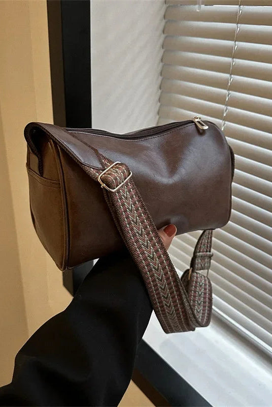 Lumina Wear Florence minimalist black crossbody bag with patterned strap, showing adjustable strap and compact handbag design.