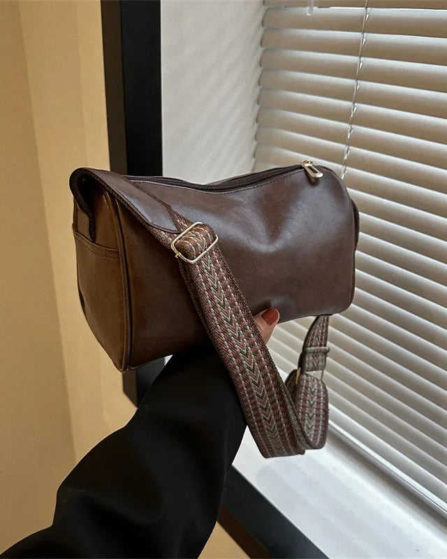 Black Lumina Florence minimalist crossbody handbag with patterned strap, featuring sleek design and adjustable strap length.