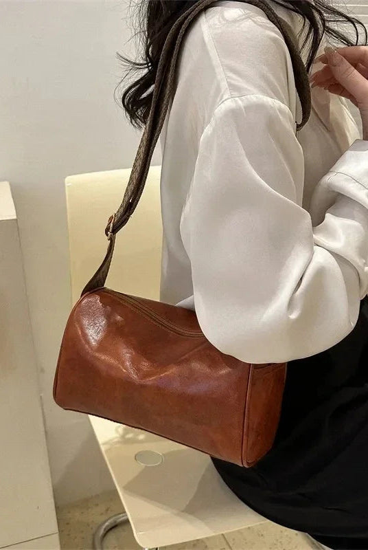 Lumina Wear Florence minimalist black crossbody handbag with patterned strap, featuring adjustable length and sleek design.