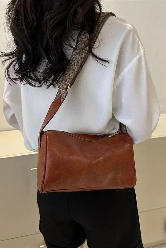Lumina Wear Florence minimalist black crossbody handbag with patterned strap, featuring sleek design and adjustable strap length.