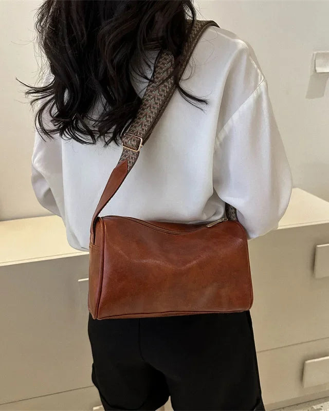 Lumina Wear Florence minimalist black crossbody handbag with patterned strap, showing adjustable strap and sleek design.