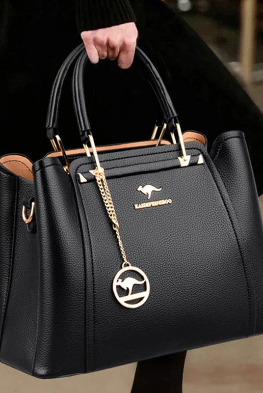 Elegant black leather handbag by Lumina Wear with gold accents, featuring a structured shape and stylish handle design.