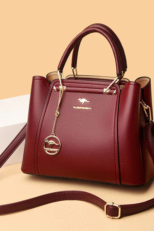 Elegant black leather handbag by Lumina Wear with gold accents, showcasing a sleek design and structured shape.