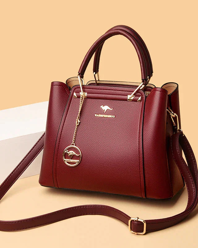 Elegant black leather handbag with gold accents from Lumina Wear, featuring a structured design and gold-tone hardware.