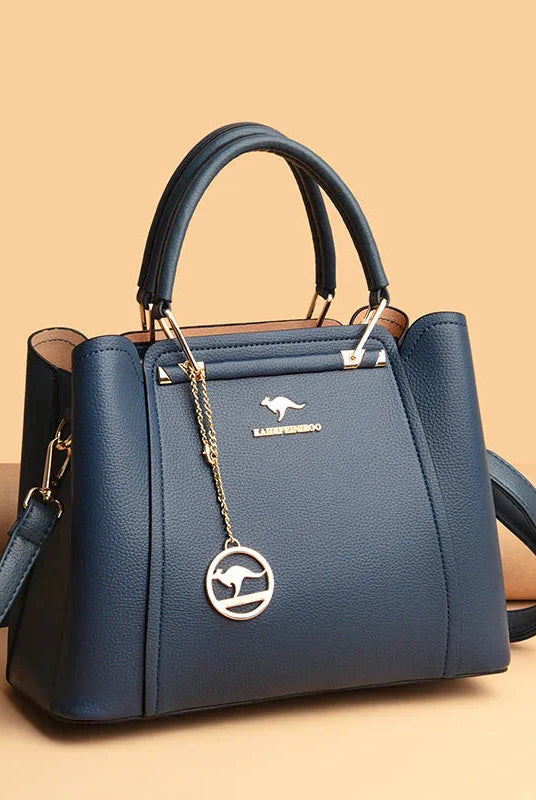 Elegant black leather handbag by Lumina Wear with gold accents, featuring a structured design and top handle for a sophisticated look.