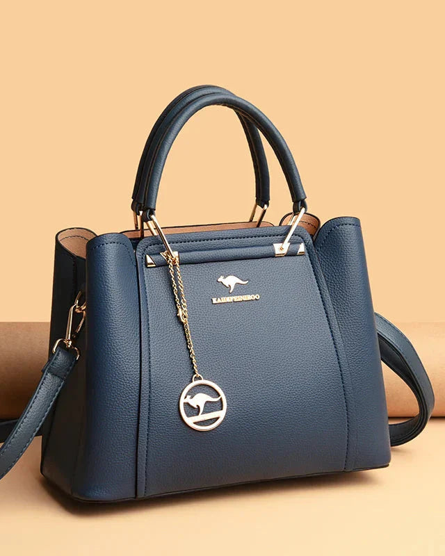 Elegant black leather Lumina Wear Isabella handbag with gold accents, featuring a structured design and top handle.