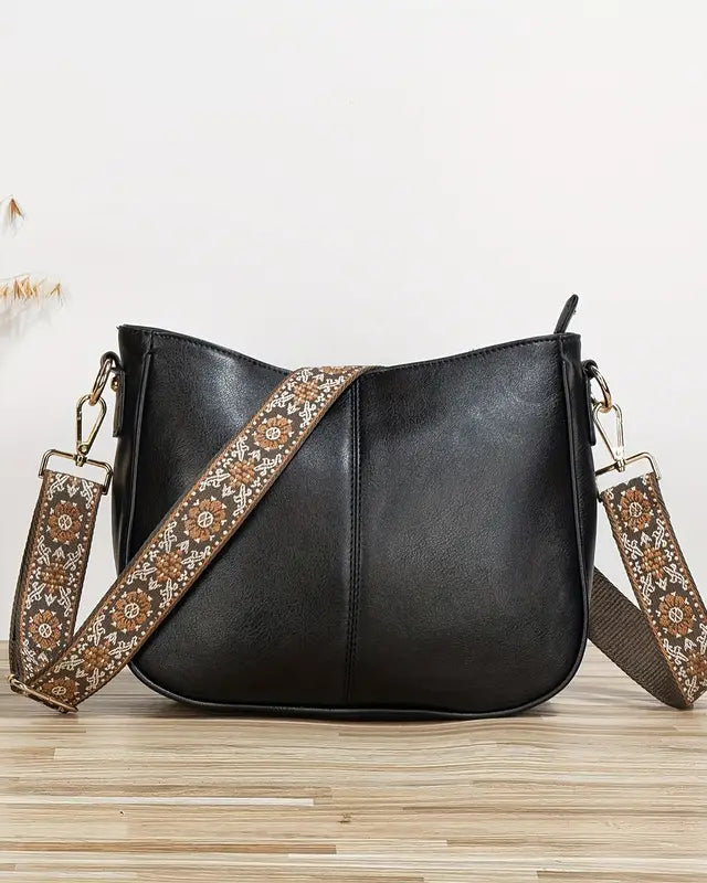 Elegant black vegan leather shoulder bag by Lumina Wear with adjustable strap, featuring a sleek design and spacious interior.