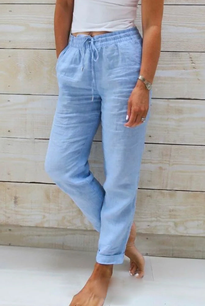 Lightweight beige linen trousers by Lumina Wear, styled on a model, showcasing elegant and comfortable casual wear.