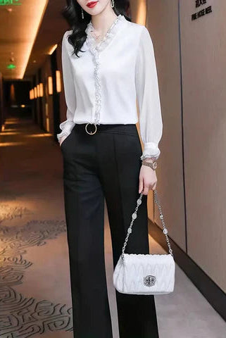 Black Isabella ruffle blouse by Lumina Wear featuring graceful long sleeves and elegant design, shown on a model.