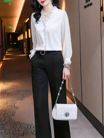 Black Isabella ruffle blouse by Lumina Wear featuring graceful long sleeves and elegant design, shown on a model.