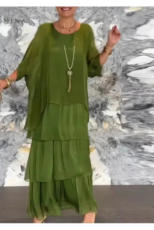 Dark green Caroline loose round neck dress by Lumina Vancouver, shown hanging on a plain background.