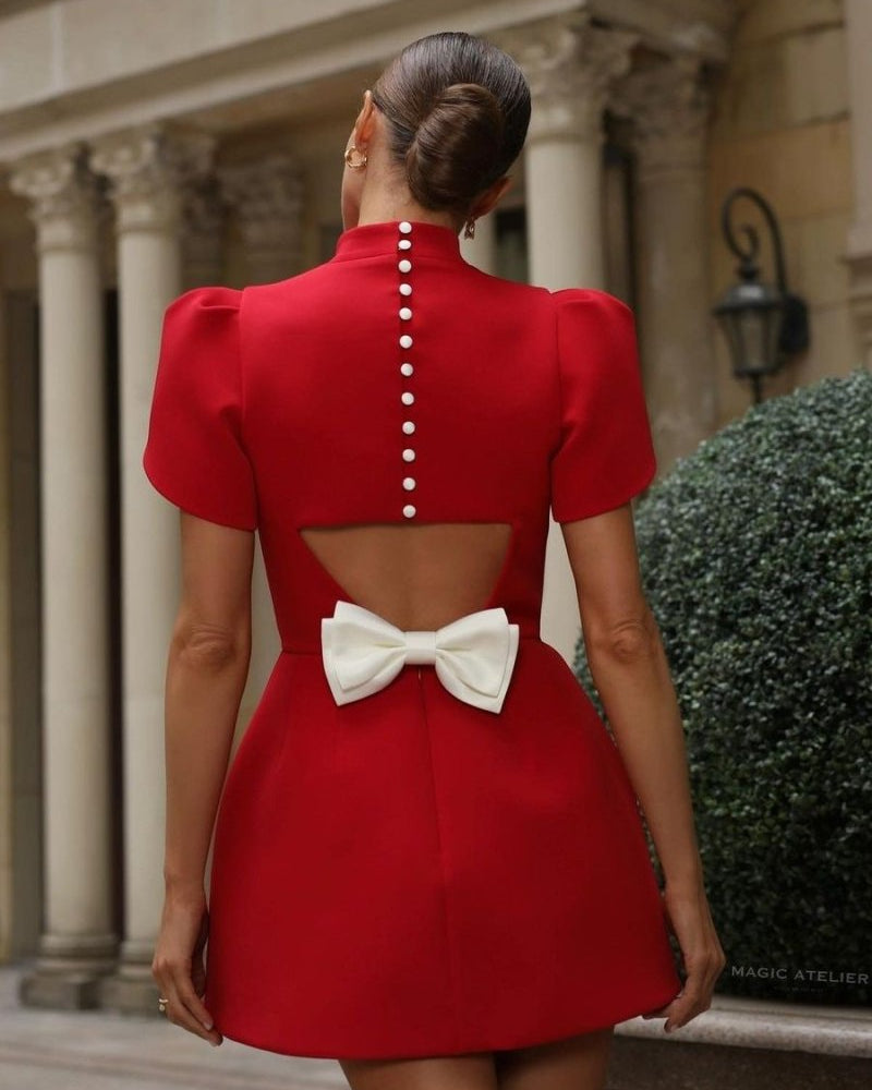 Red Lumina Wear Nova mini dress with tailored fit, open back design, and bow detail, showcased on a model against a neutral background.