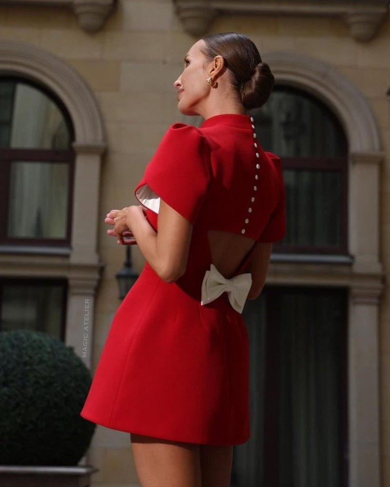 Red Lumina Wear Nova mini dress with tailored fit, open back, and bow detail, showcased on a model.