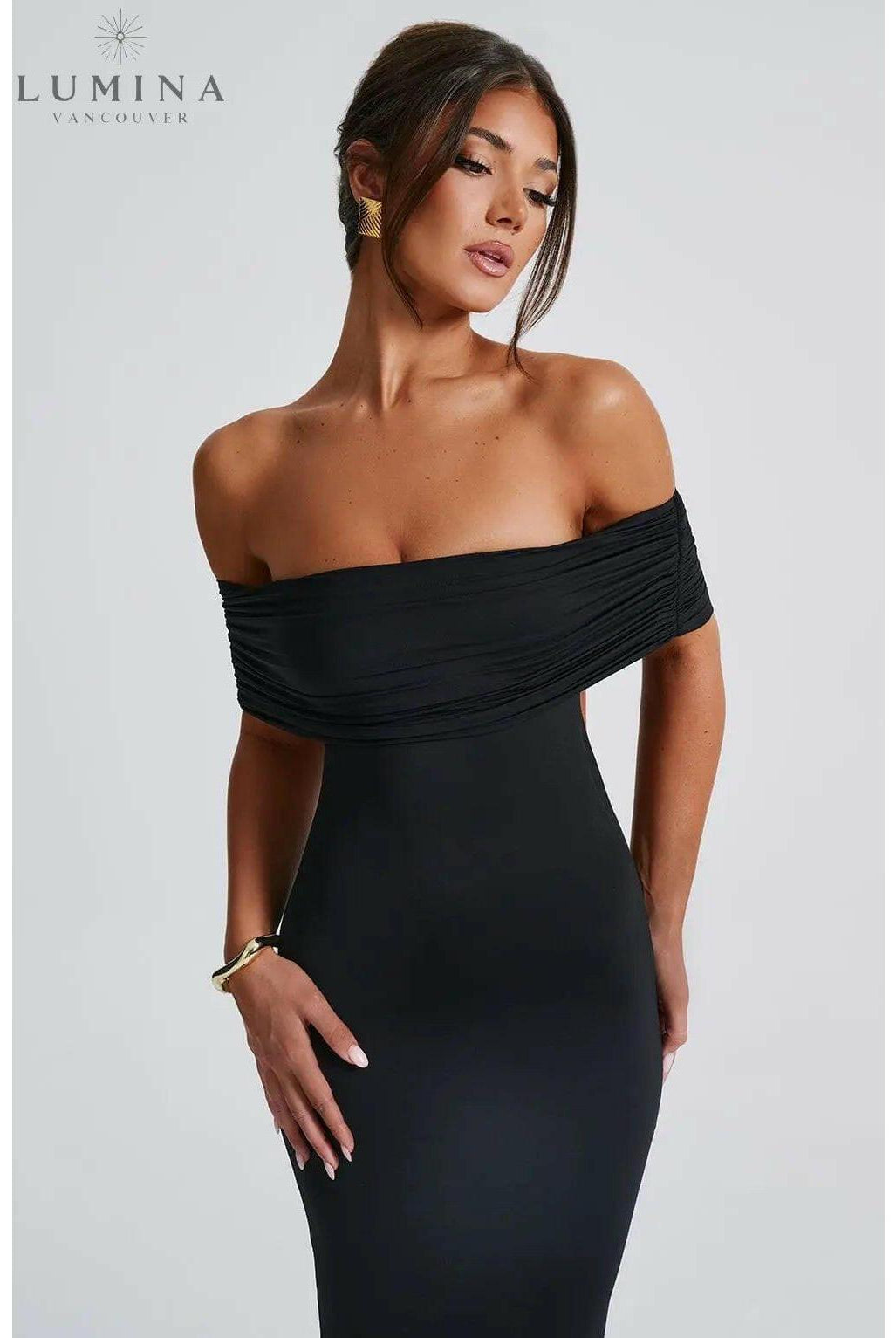 Lumina Wear Olympia elegant backless black maxi dress worn by a wedding guest, flowing length and fitted silhouette.