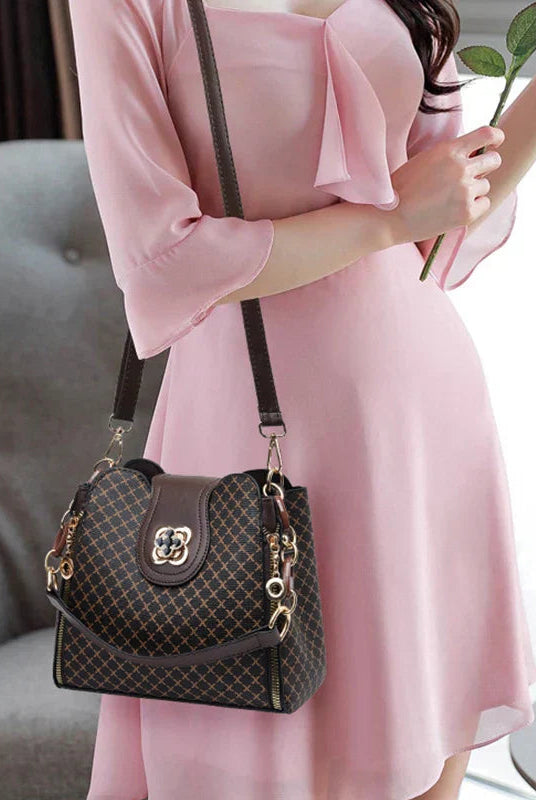 Black Marjorie quilted charm handbag with adjustable strap by Lumina Wear, featuring elegant stitching and a compact design.
