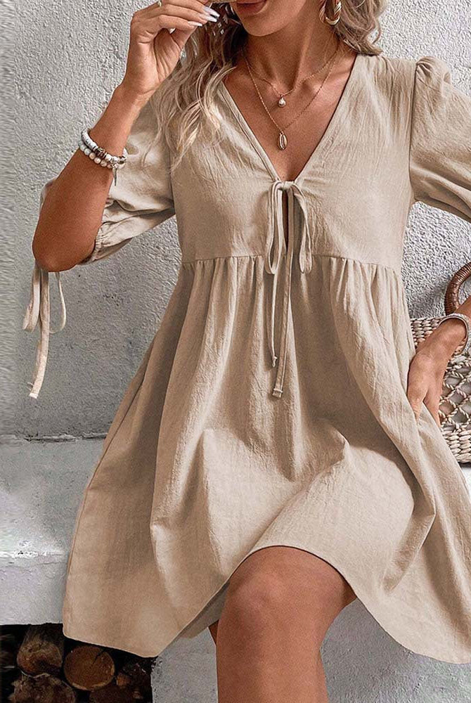 Alyx Lumina khaki A-line mini dress with deep V-neck, sleeveless design, fitted waist, and flared skirt on model.