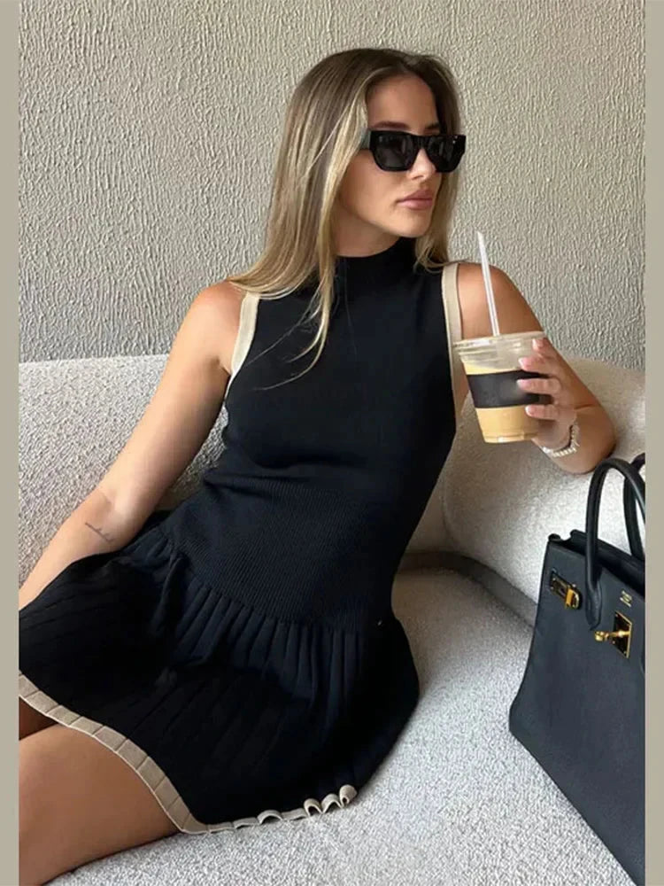 Black Nova sleeveless pleated mini dress by Lumina Vancouver, featuring a fitted bodice and flowy pleated skirt.