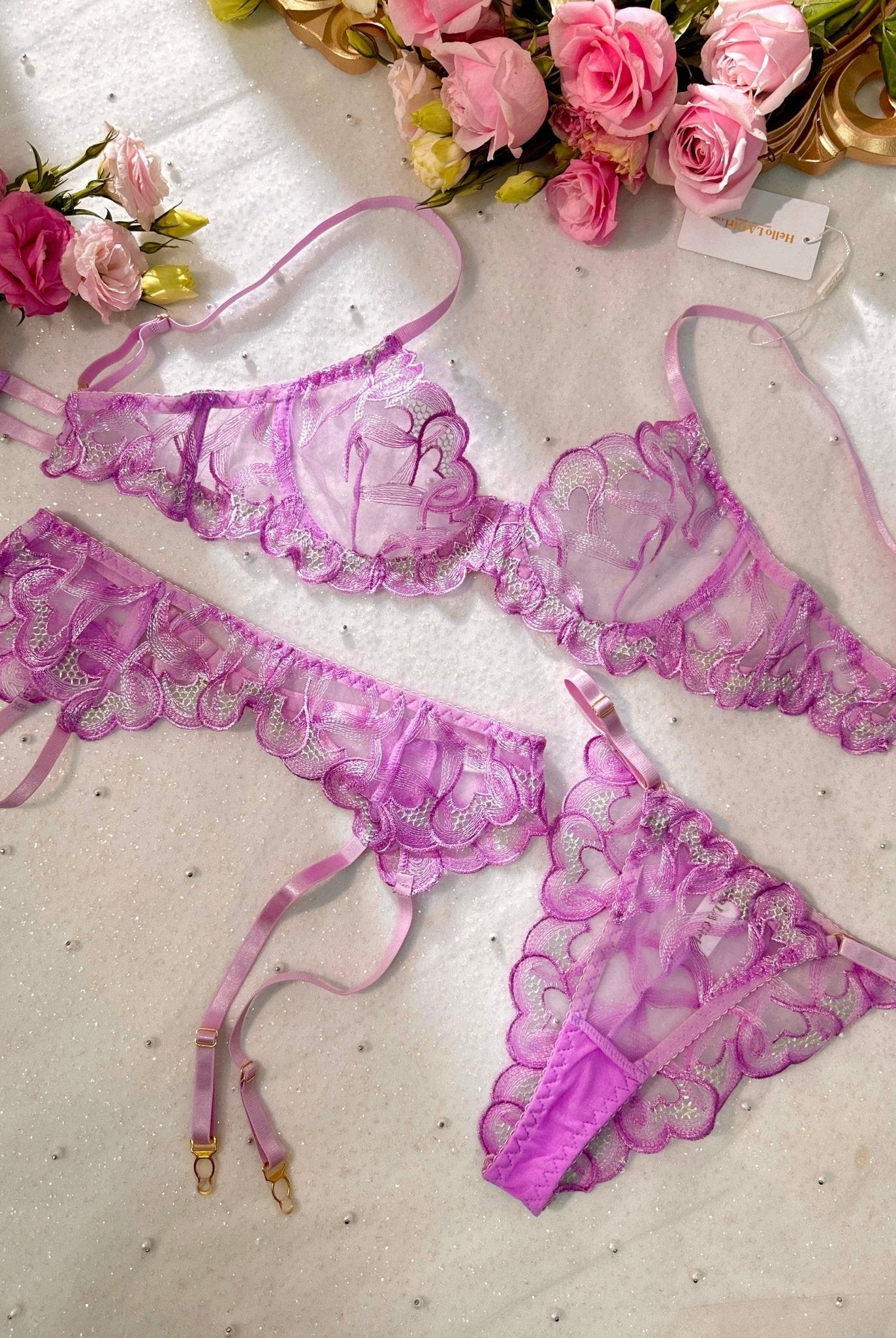 Purple embroidery lingerie set by Lumina Wear, featuring a bra, panties, and garter belt on a model.