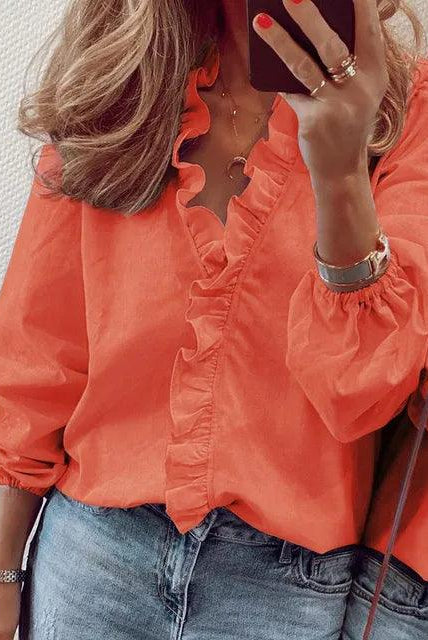 Blue Serena Lumina Wear blouse with ruffle details and V-neck, shown on a model, showcasing elegant fashion style.