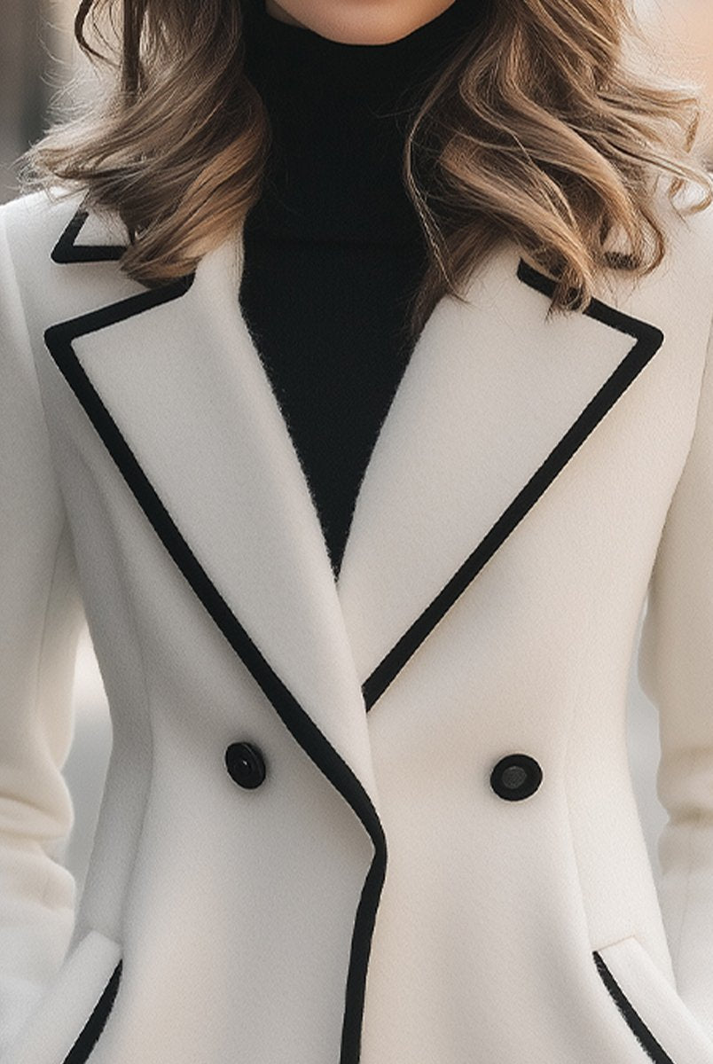 Lumina Wear Briony double-breasted white coat with trim, stylish and warm, shown on a model in a city setting.