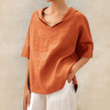 Light beige Clara Lumina Wear relaxed fit V-neck top displayed on a hanger, showcasing its simple, stylish design.