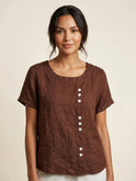 Light beige Lumina Wear Grace linen blouse with relaxed fit and button details, shown on a hanger.