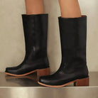 Black knee-high boots for women by Lumina Wear featuring a sleek design and stacked heel, styled with the Isabella collection.